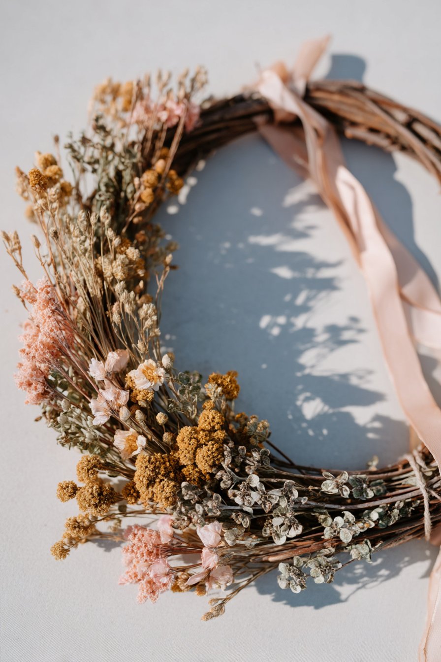 Astkranz mit getrockneten Frühlingsblumen und Schleifen