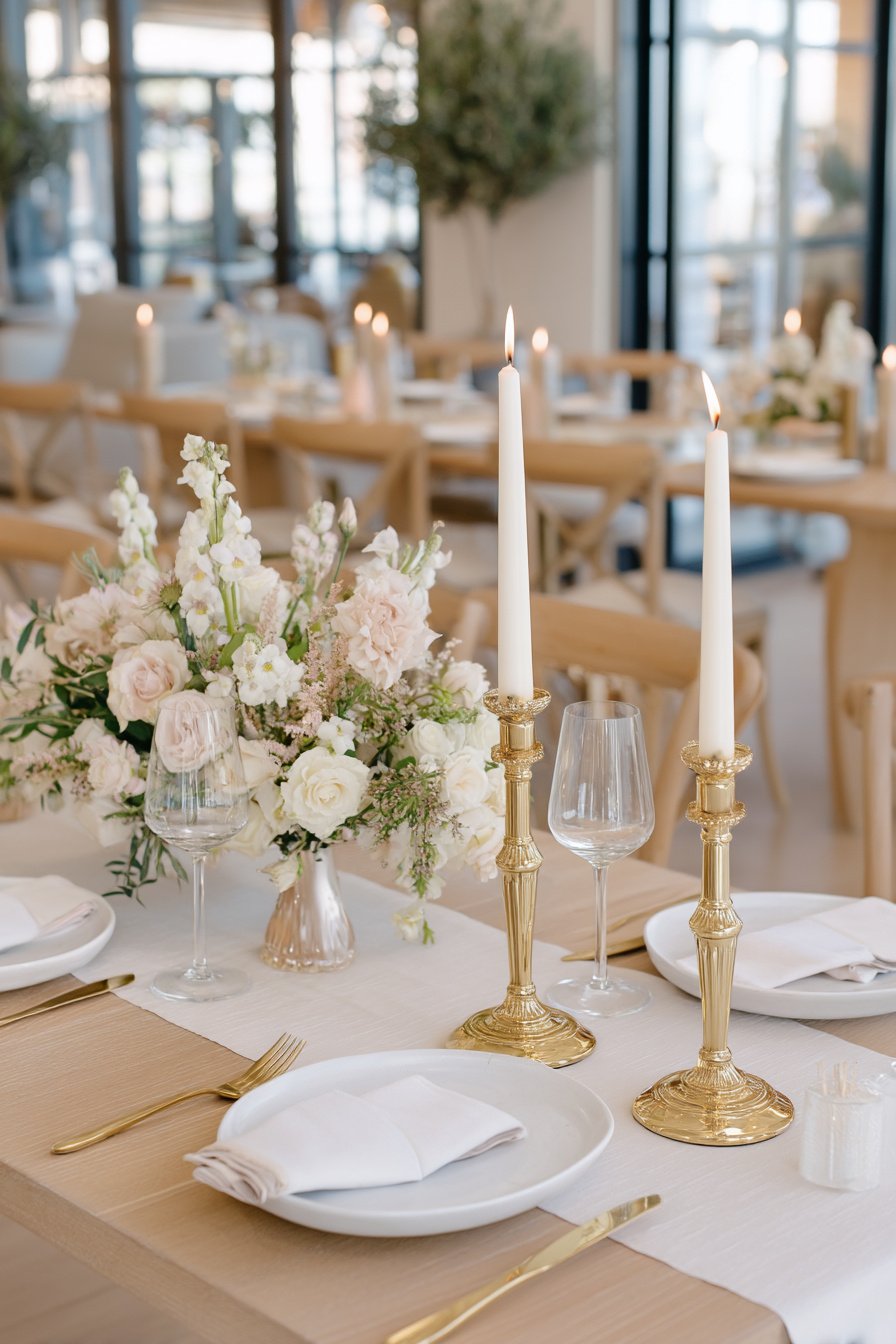 Goldene Kerzenleuchter mit weißen Kerzen auf Hochzeitstisch