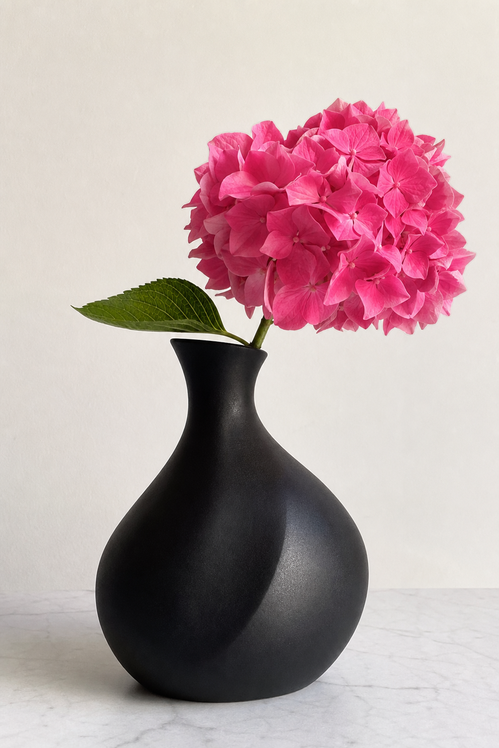 Pinke Hortensienblüte in schwarzer Vase als Tischdeko